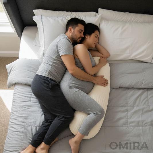 Couple lying on a bed with a slim white pregnancy pillow that supports comfort and closeness.